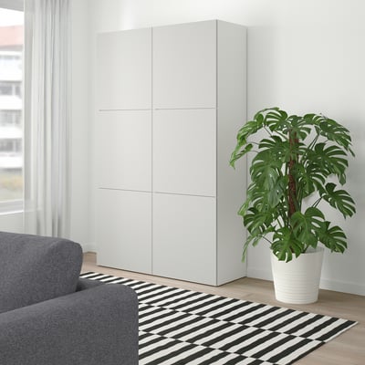 Modern living room with white BESTÅ cabinet, grey sofa, and green plant.
