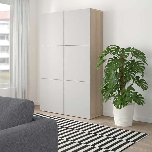 Minimalist room with BESTÅ cabinet, sofa, rug, plant, window.