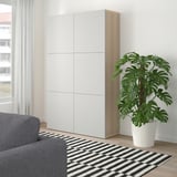 Minimalist room with BESTÅ cabinet, sofa, rug, plant, window.