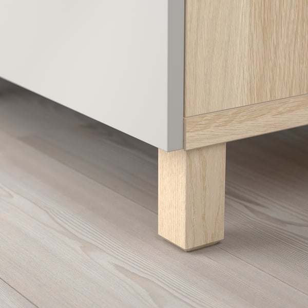 Modern wooden cabinet with light oak legs on a wooden floor. Square leg design, part of BESTÅ series.