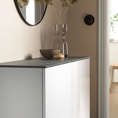 Modern console table with BESTÅ black marble top. Vase and bowl decor. Mirror above. Room visible in background.