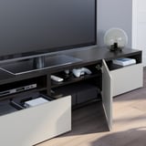 Modern tv stand with open drawers, showing game controllers and remotes. A large flat-screen tv sits atop.