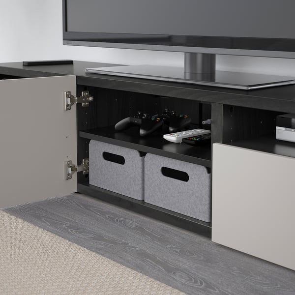 Tv stand with open shelf holding gaming controls and remotes, featuring cable management and wall-mount capability.