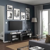 Modern living room with BESTÅ tv bench, flat screen, photos, lamp, glass table.