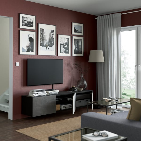 Modern living room with maroon walls, BESTÅ tv bench, glass coffee table, large window.
