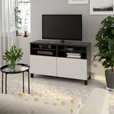 Modern black & white living room with BESTÅ tv bench, plants, and natural light.