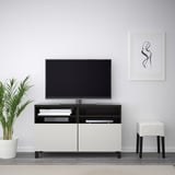 Modern living room with BESTÅ tv stand, flat screen tv, books, plant, stool, gray rug - minimalist.