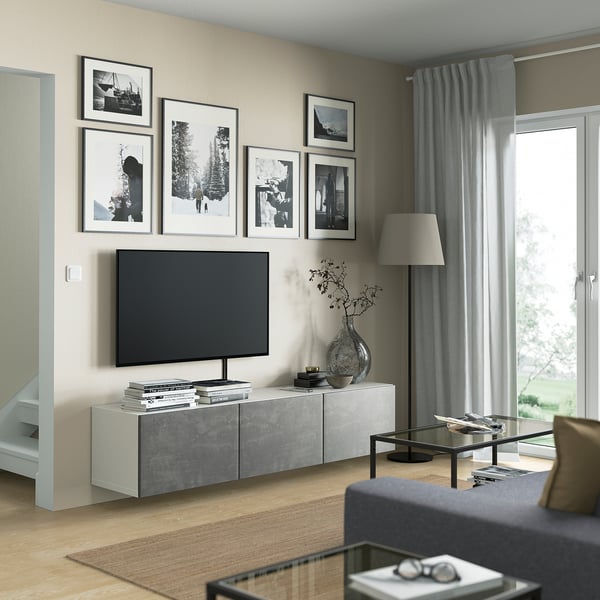 Modern living room with BESTÅ tv bench in gray, flat screen tv, framed photos, wooden floor, and a gray curtain.