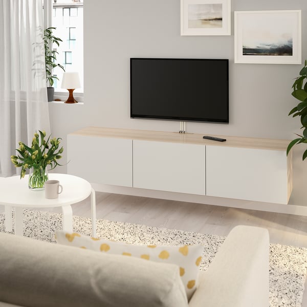 Modern living room with BESTÅ, flat screen, and yellow sofa. Bright decor with clean lines.