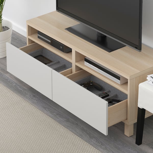 Wood tv stand with remote and controller in drawer, flat screen tv, dvd, soundbar, white wall.