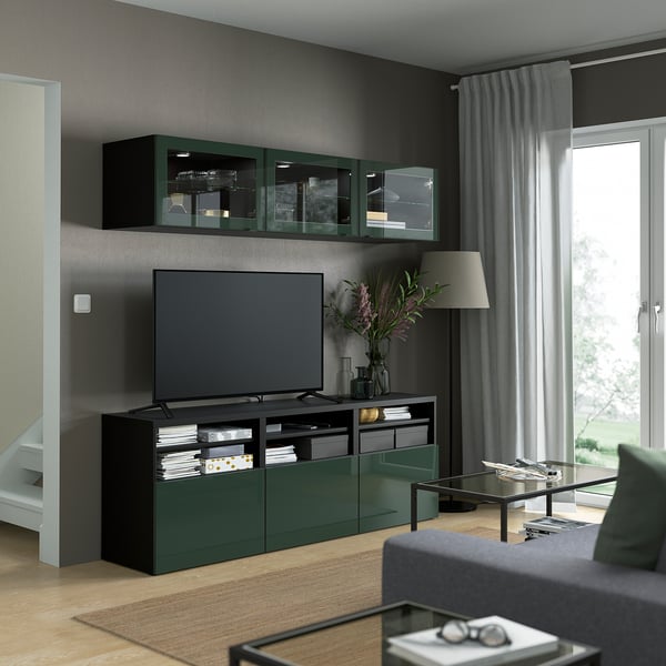 Modern living room with black/green BESTÅ tv storage unit, flat-screen tv, adjustable shelves, light curtains, wooden floor.