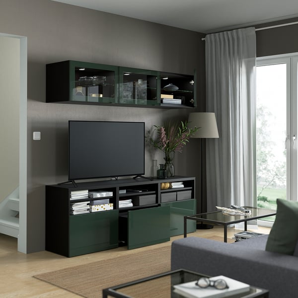 Modern living room with BESTÅ tv unit. It adjustable shelves, cable management, and a wall-mounted cabinet. Dark decor with plants and books.