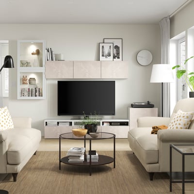 Modern living room with white BESTÅ tv unit, light wood floors, beige sofas, a black coffee table, and decor.