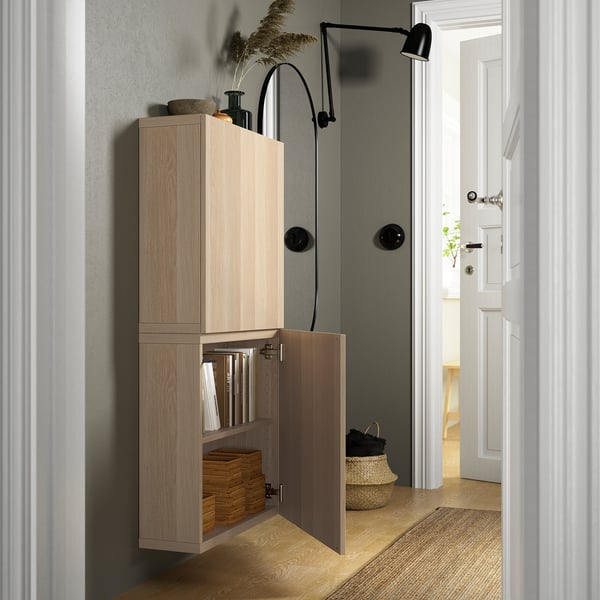 Light wood cabinet, wall-mounted with doors ajar, revealing organised items. Adjustable hinges and removable doors.