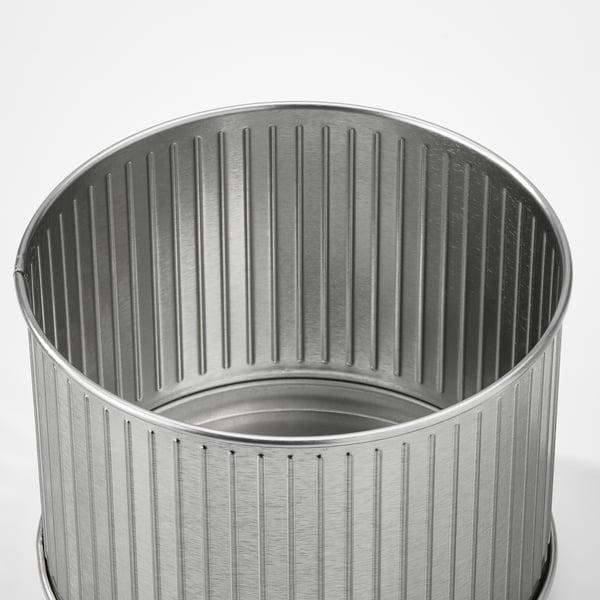 Silver metal trash can with vertical ridges.