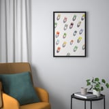 Framed art BILD above yellow armchair, colorful pebbles, books, mug, plant.