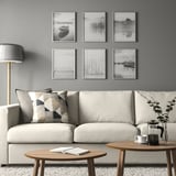 Modern living room with white couch, BILD posters, coffee table, lamp, and plant.