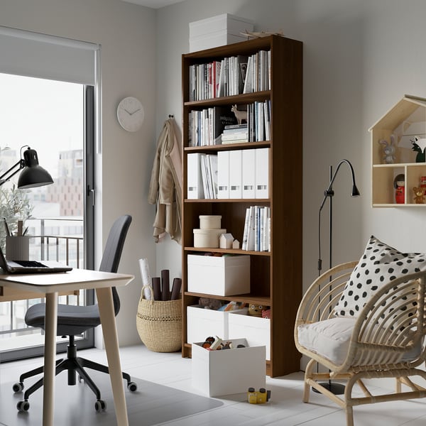 Home office: BILLY bookcase stands tall with wooden shelves. Surrounded by desk, chair, and toys. Perfect for storage and display.