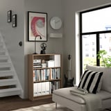 Modern living room with BILLY bookcase, couch, guitar, and urban view.
