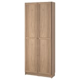 A BILLY bookcase in light oak color, made of particleboard and fibreboard, with two panel doors and adjustable shelves for dust-free storage.