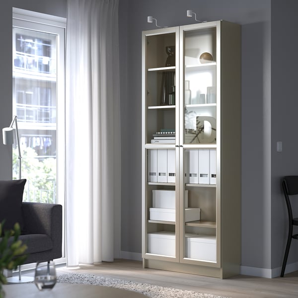 BILLY white bookcase with glass doors next to window.