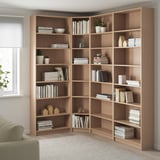 Corner BILLY bookcase in light oak, reaching ceiling with books and decor.