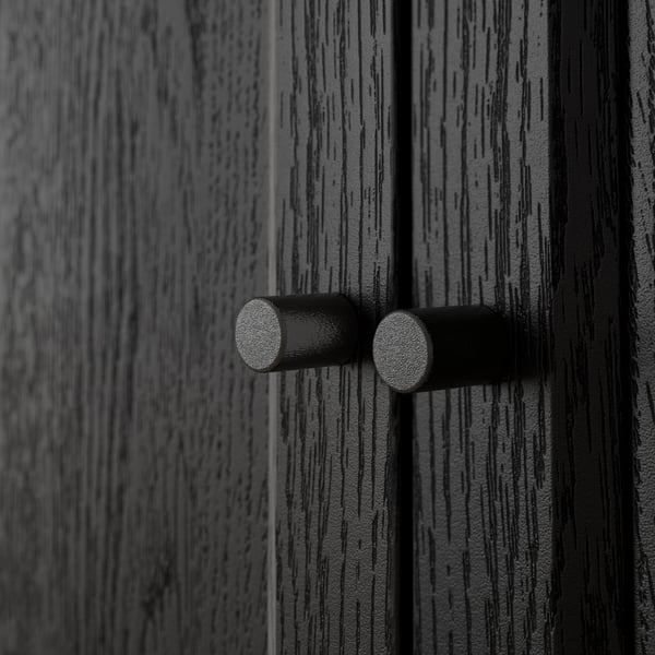 Close-up of black wooden texture with two cylindrical knobs, showcasing BILLYs quality craftsmanship.