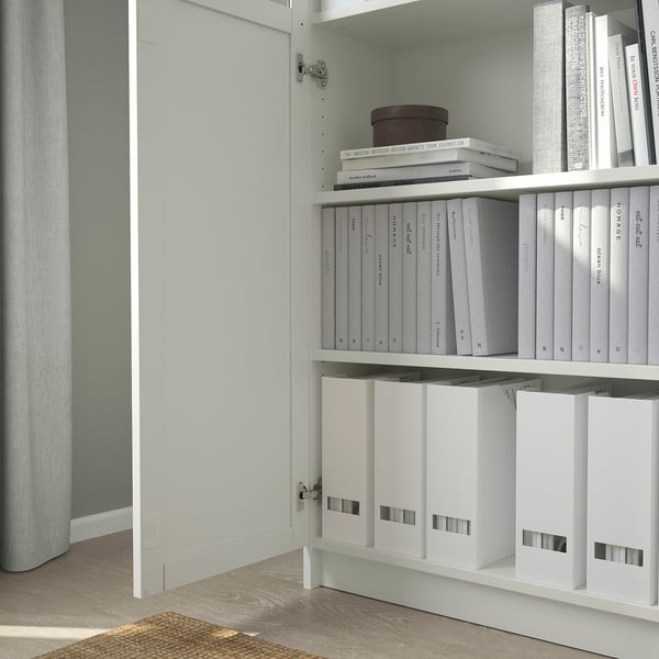 A BILLY bookcase with adjustable shelves and a white door, displaying neatly organized files and books.