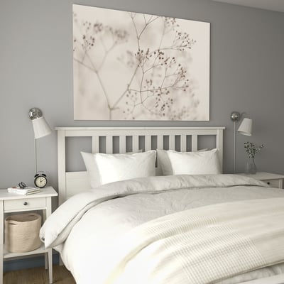 Modern bedroom with BJÖRKSTA bed, grey walls, floral canvas, white bedding, nightstands, alarm clock, basket.