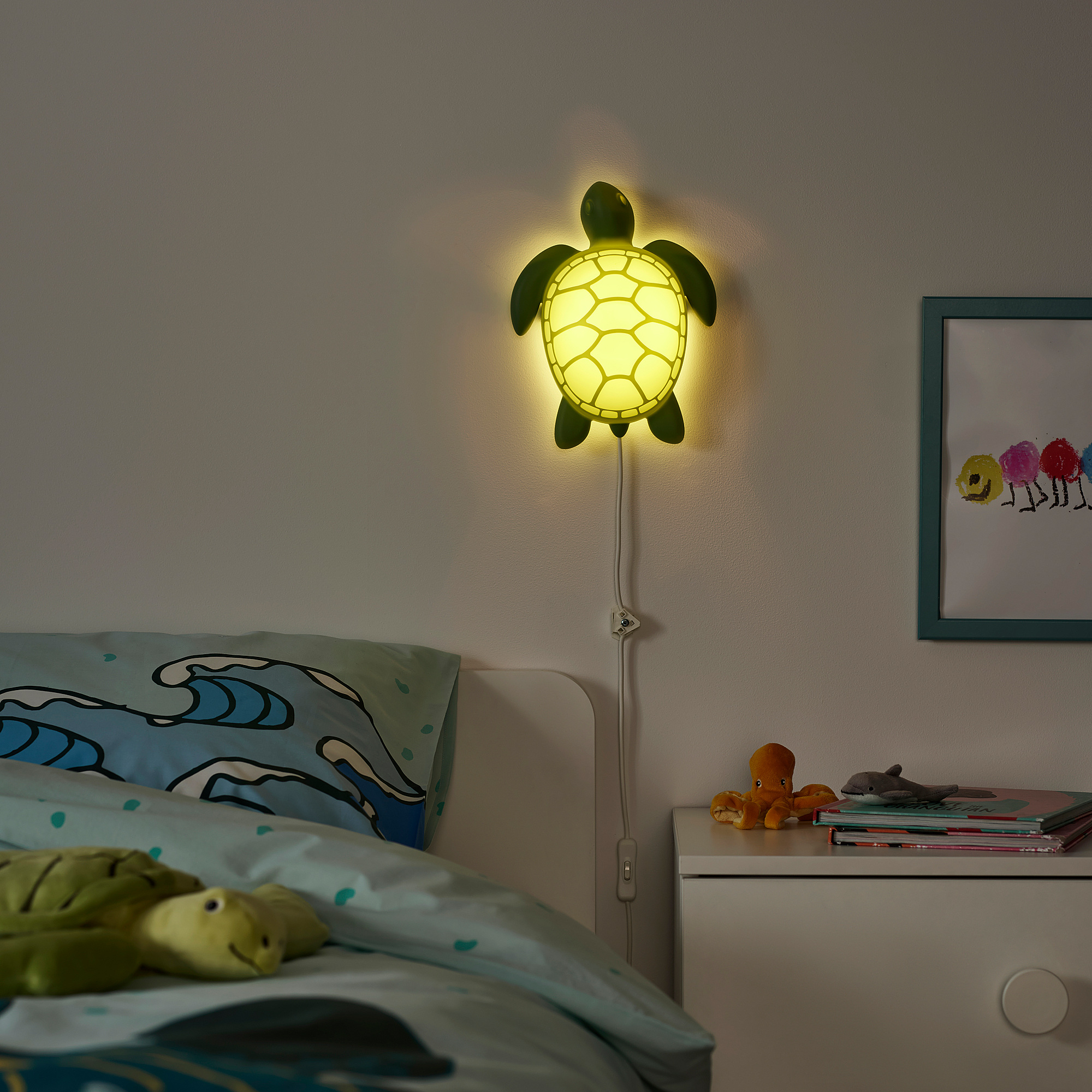 Green BLÅVINGAD turtle lamp, recycled plastic, soft yellow light, above bed, orange octopus toy, ocean theme.