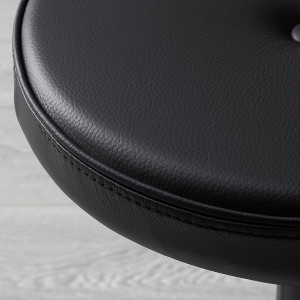 Close-up of smooth, round, black leather chair seat, showcasing high-quality stitching and texture.