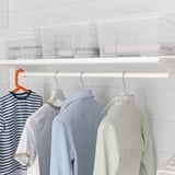 Neatly organized closet with hanging rod and storage bins for laundry.