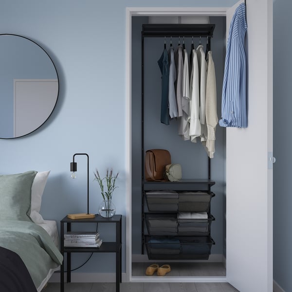 Modern blue bedroom with grey BOAXEL closet, neat clothes, and nightstand lamp.