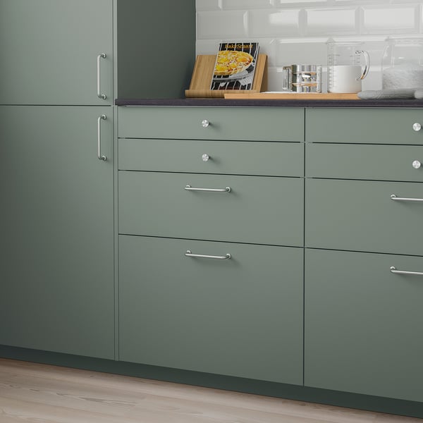 Modern green kitchen cabinets with metallic handles, sleek design, appear larger than average items.