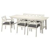 A white outdoor dining set with a rectangular table and seven matching chairs, six with dark gray cushions.