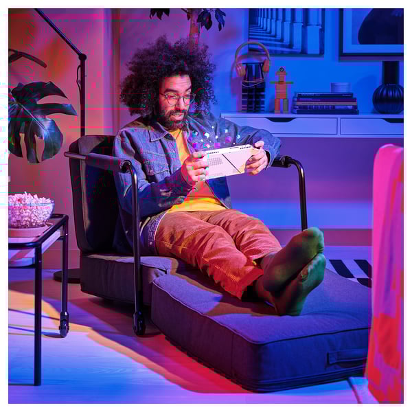 Man in colorful outfit reads, lounging in transformable armchair/chair with seat cushion folded out.