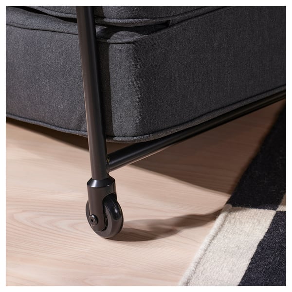 Close-up of a rolling chairs caster on a wooden floor. The chair has a dark upholstered seat with a sturdy metal frame.