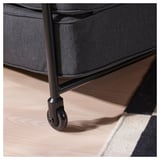 Close-up of a rolling chairs caster on a wooden floor. The chair has a dark upholstered seat with a sturdy metal frame.