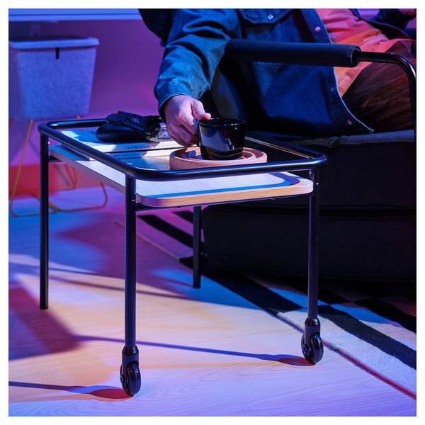 Person rolling side table with snacks and drink.
