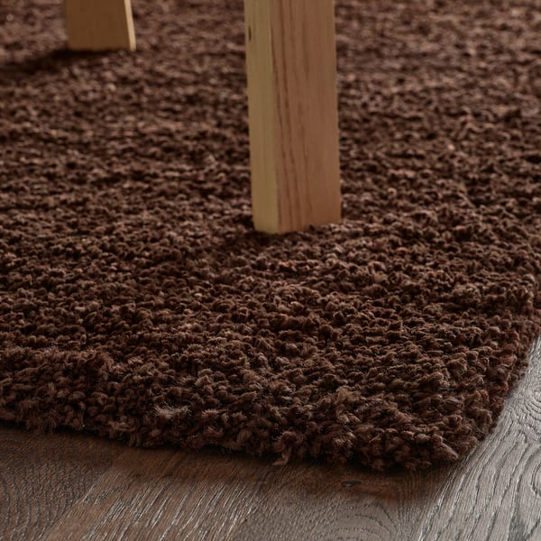 Brown shaggy rug under wooden furniture, illustrating its soft, durable, and stain-resistant properties for comfort and warmth.
