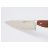Close-up of a high-quality cooks knife with a wooden handle, sharp stainless steel blade, and brand name ikea engraved on it.