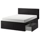 Black BRIMNES bed with white mattress, sleek modern design, dark wood finish, four storage drawers.