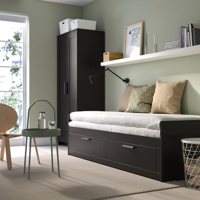 Dark grey BRIMNES day-bed, 2 drawers, converts to single/double. Decorated with green, wood, and natural light.