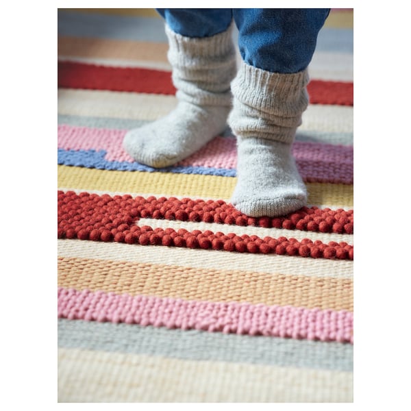 Colorful striped rug, grey socks, feet standing.