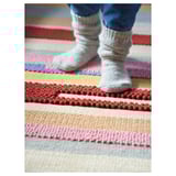Colorful striped rug, grey socks, feet standing.