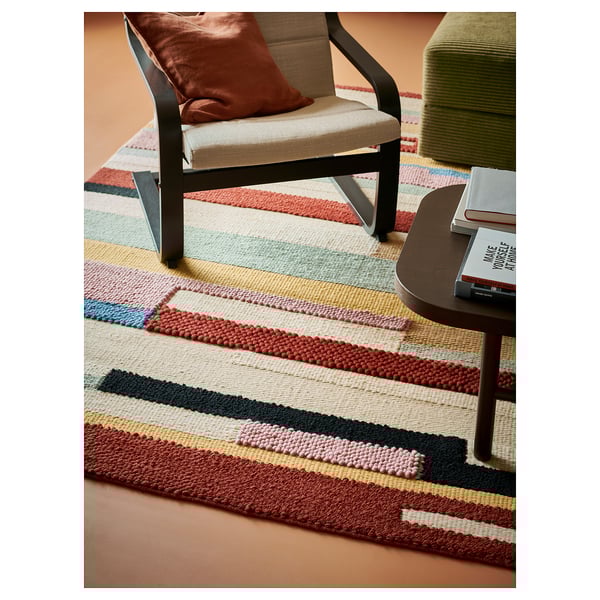 Bright, multicolored, striped, handwoven wool rug, with black, red, and beige seats.