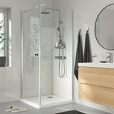 Modern bathroom with BROGRUND shower, glass door, chrome, minimalist design. White tiles, dark towels, wooden vanity.