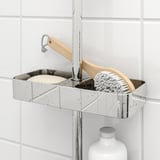 Metal shower shelf holds brush, soap, and bottle. Rests on rail, with adjustable height and drainage holes.