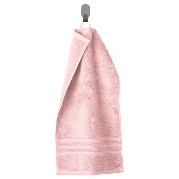 Light pink organic cotton towel with a woven border hangs neatly on a silver hook. Soft, absorbent, and elegant.