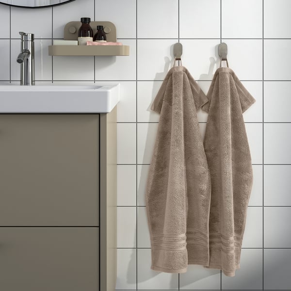 Modern bathroom with BROKGLIM towels, sink, and mirror. Organic cotton, toiletries shelf.